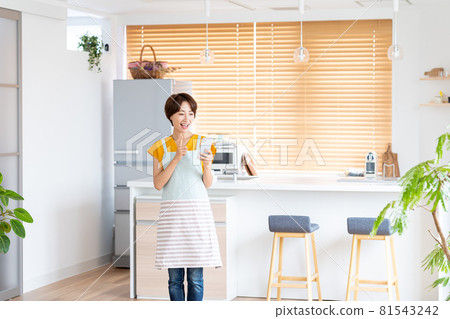 站立在廚房裡的微笑的中部婦女 81543242