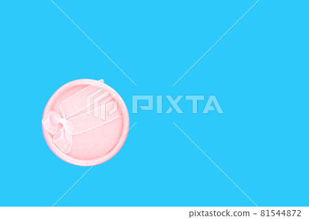Round pink gift box with pink ribbon on a light blue background with place for text. Round pink gift box with pink ribbon on a light blue background with place for text. 81544872
