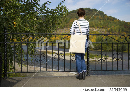 Woman in striped long sleeve shirt holding tote bag mockup 81545069