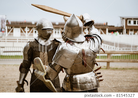 Reenactment of the battle of medieval knights in heavy armor on wooden swords Reenactment of the battle of medieval knights in heavy armor on wooden swords 81545327