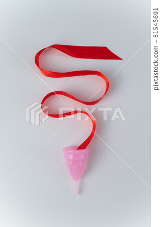 Pink menstrual cup and red satin ribbon on a white background Pink menstrual cup and red satin ribbon on a white background 81545691
