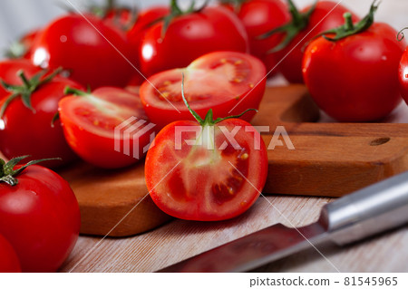 Red tomatoes and knife on wooden cutting board Red tomatoes and knife on wooden cutting board 81545965