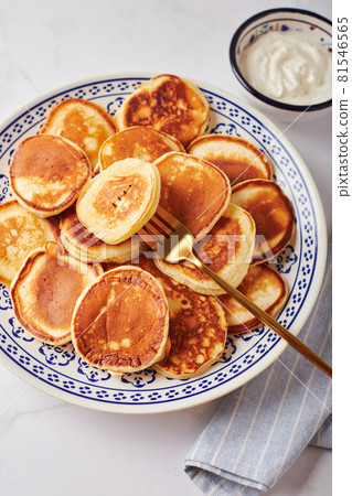 Sweet pancakes with sour cream on a plate on a white table Sweet pancakes with sour cream on a plate on a white table 81546565