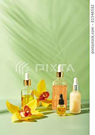 Cosmetic care products in glass bottles with orchid flowers - serums, cream, gel, oils. Concept for face and body care, wellness and spa, tropical relaxation 81546582