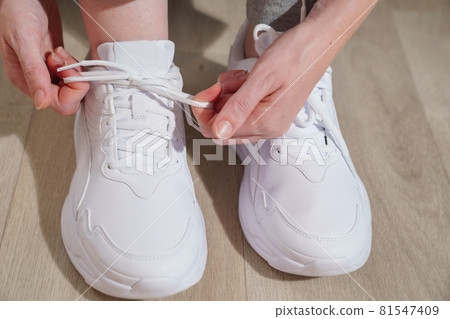 Tie the laces on the white sneakers women's hands close-up. sports, running 81547409