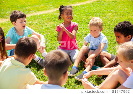 Group of elementary school children chatting on the green lawn 81547962