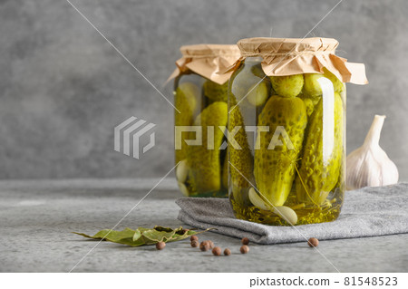 Canned vegetables cucumber in glass jars on grey background. 81548523