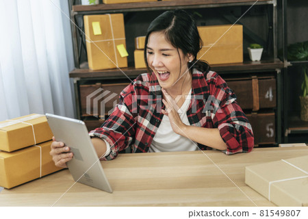 Asian woman startup small business at home office. Online seller entrepreneur young asian woman use tablet checking online order. Woman using tablet check stock goods supply delivery package shipping Asian woman startup small business at home office. Online seller entrepreneur young asian woman use tablet checking online order. Woman using tablet check stock goods supply delivery package shipping 81549807