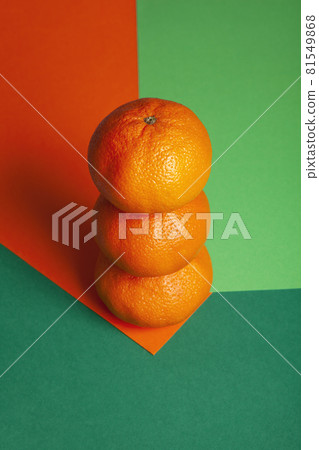 tower of 3 oranges isolated on green and orange background 81549868