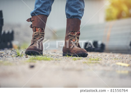 Men wear construction Boots safety footwear for worker at construction site. Engineer Wear Jeans Brown Boots Worker on Background of Refinery. Engineer safety industry fashion footwear walking outdoor Men wear construction Boots safety footwear for worker at construction site. Engineer Wear Jeans Brown Boots Worker on Background of Refinery. Engineer safety industry fashion footwear walking outdoor 81550764
