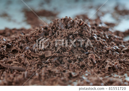 Grated chocolate on a white table. Preparation for dessert. The background in blur. Grated chocolate on a white table. Preparation for dessert. The background in blur. 81551720