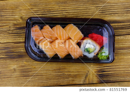 Sushi rolls Philadelphia in plastic box on wooden table. Top view. Sushi for take away or delivery of sushi in plastic container 81551769