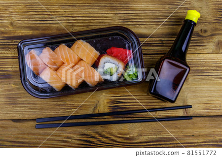 Sushi rolls Philadelphia in plastic box on wooden table. Top view. Sushi for take away or delivery of sushi in plastic container 81551772