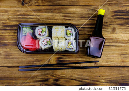 Uramaki sushi rolls with surimi in plastic box on wooden table. Top view. Sushi for take away or delivery of sushi in plastic container 81551773