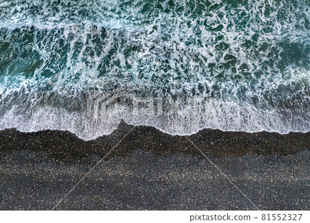 Stormy waves with white sea foam breaking on dark sandy beach, view from directly above Stormy waves with white sea foam breaking on dark sandy beach, view from directly above 81552327