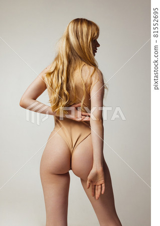Back view of young beautiful slim tanned woman in lingerie posing isolated over light studio background. Natural beauty, wellness, healthy lifestyle concept. 81552695