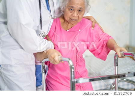Asian nurse physiotherapist doctor care, help and support senior or elderly old lady woman patient walk with walker at hospital ward, healthy strong medical concept. 81552769