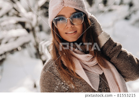 A girl in a sweater and glasses in winter in a snow-covered forest 81553215