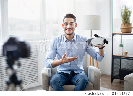 Arab male vlogger making tech product review, presenting VR headset, shooting video for technology blog at home Arab male vlogger making tech product review, presenting VR headset, shooting video for technology blog at home 81553237