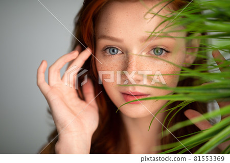 Ginger-Haired Young Woman Touching Red Hair Posing With Plant, Studio Ginger-Haired Young Woman Touching Red Hair Posing With Plant, Studio 81553369