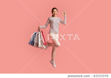 Big Sales Concept. Happy Asian Female Jumping With Shopping Bags And Showing Ok Gesture, Excited Young Korean Woman Enjoying Seasonal Discounts, Posing Isolated Over Pink Background, Copy Space Big Sales Concept. Happy Asian Female Jumping With Shopping Bags And Showing Ok Gesture, Excited Young Korean Woman Enjoying Seasonal Discounts, Posing Isolated Over Pink Background, Copy Space 81553370