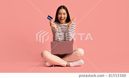 Online Payments. Cheerful young asian woman sitting with laptop and credit card Online Payments. Cheerful young asian woman sitting with laptop and credit card 81553389