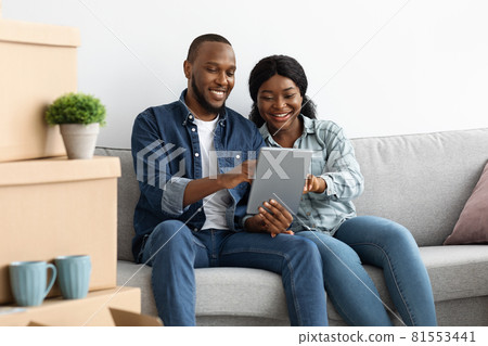 Black Couple Ordering Online With Digital Tablet After Moving To New Apartment 81553441