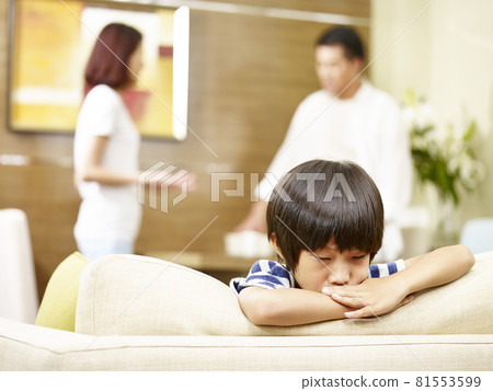 asian child appears sad and unhappy while parents quarreling in the background asian child appears sad and unhappy while parents quarreling in the background 81553599