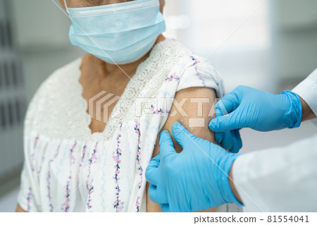 Elderly Asian senior woman wearing face mask getting covid-19 or coronavirus vaccine by doctor make injection. Elderly Asian senior woman wearing face mask getting covid-19 or coronavirus vaccine by doctor make injection. 81554041