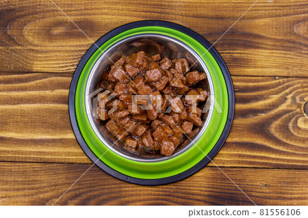 Canned food for cats or dogs in green metal bowl on wooden floor. Top view Canned food for cats or dogs in green metal bowl on wooden floor. Top view 81556106