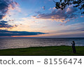 A woman touching her cell phone while bathing in the setting sun at Shimoumagahama Beach in Fukuoka Prefecture 81556474