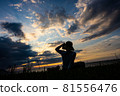 A woman sitting and watching the sunset at Shimoumagahama beach in Fukuoka prefecture 81556476
