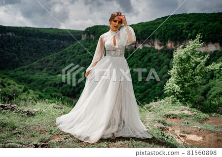 woman in a wedding dress posing in the mountains. fashionable clothes for bride woman in a wedding dress posing in the mountains. fashionable clothes for bride 81560898