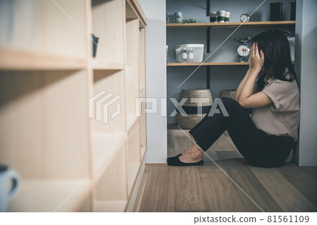 一個女人獨自躺在黑暗房間的地板上,用手摀住臉。 一個女人獨自躺在黑暗房間的地板上,用手摀住臉。 81561109