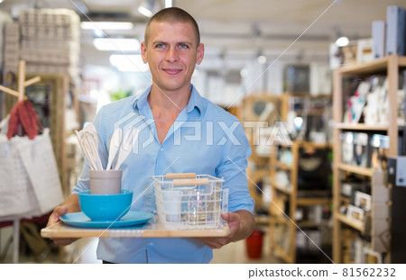 Man customer holding purchases and walking in household goods store 81562232
