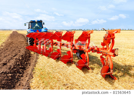 Agricultural tractor coupled to a metal plow on a harvested wheat field. Agricultural tractor coupled to a metal plow on a harvested wheat field. 81563645