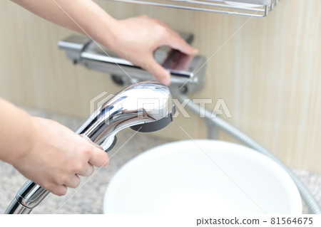Female hand twisting the shower faucet 81564675