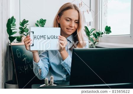 Young female teacher sitting at desk and using laptop showing HOMEWORK text at home. e Education Back to school. Student learning online class. Distance learning. Exam preparation Young female teacher sitting at desk and using laptop showing HOMEWORK text at home. e Education Back to school. Student learning online class. Distance learning. Exam preparation 81565622