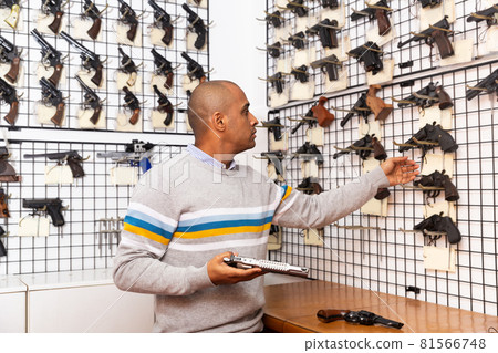 Latino choosing sporting and hunting revolvers in gunsmith shop Latino choosing sporting and hunting revolvers in gunsmith shop 81566748