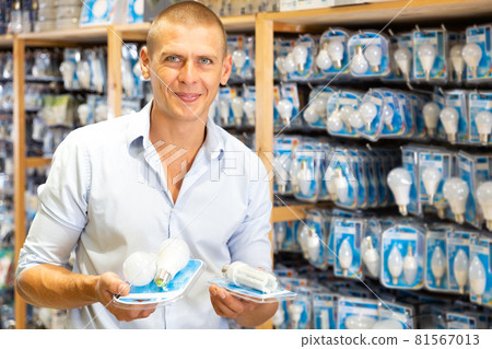 Man choosing energy saving light bulbs 81567013
