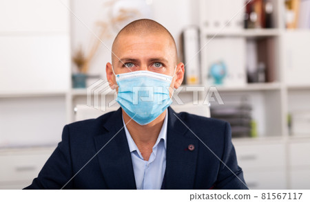 Professional business man in protective medical mask using laptop at workplace Professional business man in protective medical mask using laptop at workplace 81567117