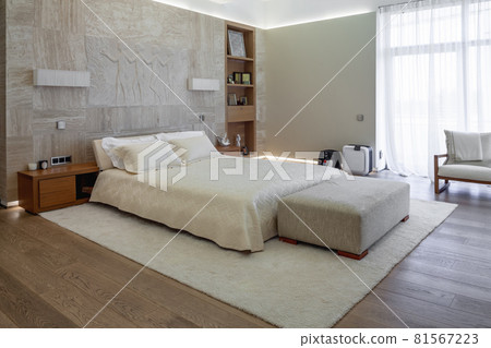 Cozy bedroom with wide window and double bed near marble wall decorated with sculptural pane 81567223