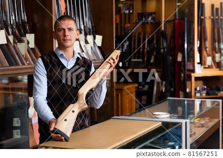 Gun shop salesman with air rifle in hand closeup Gun shop salesman with air rifle in hand closeup 81567251