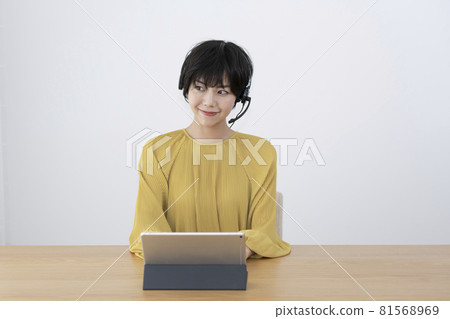 一位戴著耳機並在房間里遠程工作的年輕女性 81568969