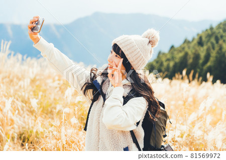 A woman taking a selfie at the top of the mountain 81569972