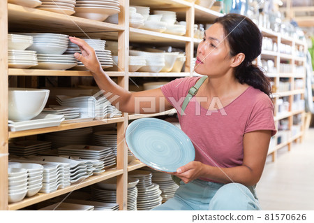 Asian woman choosing dishes at decor store Asian woman choosing dishes at decor store 81570626
