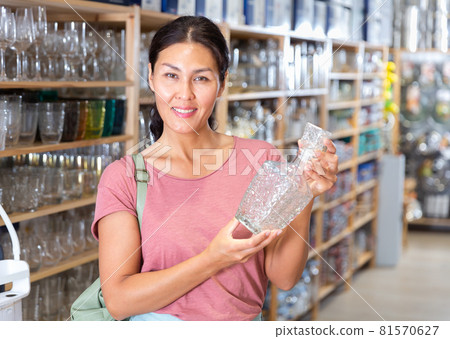 Asian woman choosing glassware in store Asian woman choosing glassware in store 81570627