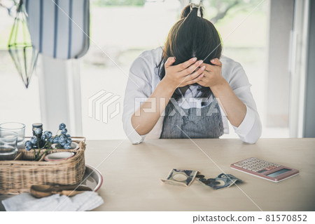 A woman is holding her head with a calculator and money in the room woman money A woman is holding her head with a calculator and money in the room woman money 81570852