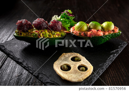 Salmon tartare and avocado salad on a black background Salmon tartare and avocado salad on a black background 81570956