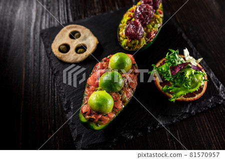 Salmon tartare and avocado salad on a black background Salmon tartare and avocado salad on a black background 81570957